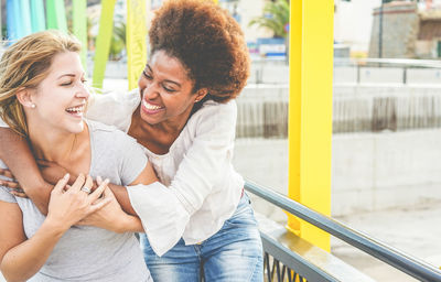 Happy lesbian couple embracing on bridge in city