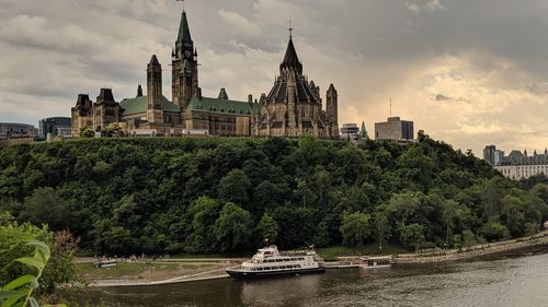 Panoramic view of buildings and river against cloudy sky