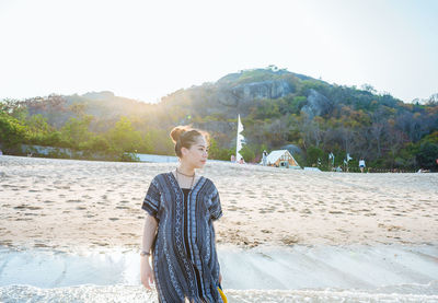 Young woman standing on beach against clear sky