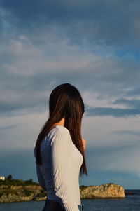 Side view of woman looking at sea against sky