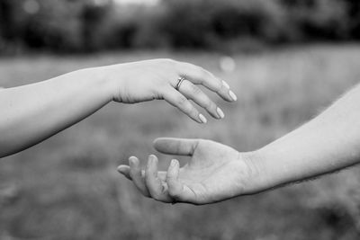 Cropped image of woman giving hand to man against blurred background