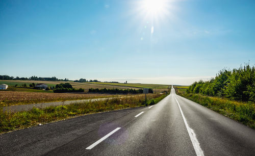 Road amidst field against sky