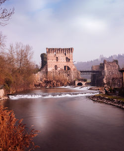 View of castle by river against sky