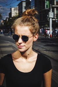 Close-up of young woman wearing sunglasses on street in city