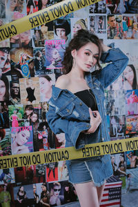 Portrait of young woman standing against graffiti wall