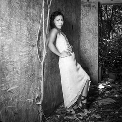 Side view portrait of young woman standing by wall in forest