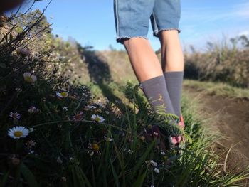 Low section of woman on grassy field against sky