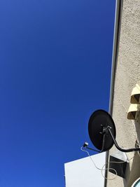 Low angle view of telephone pole against clear blue sky