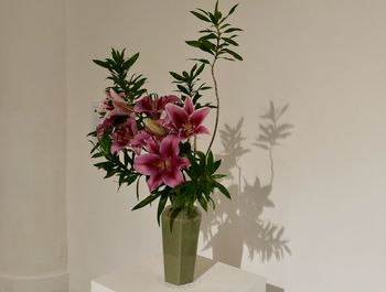 Close-up of pink flower vase on table against wall