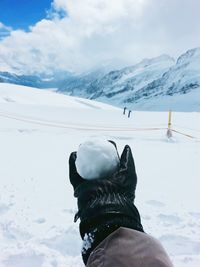 Cropped image of hand holding snowball on snow covered field