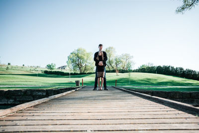 Full length portrait of man standing on field against clear sky