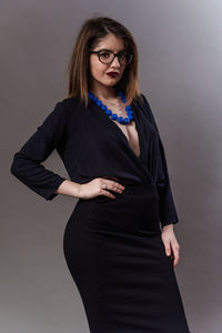 Portrait of smiling woman standing against gray background