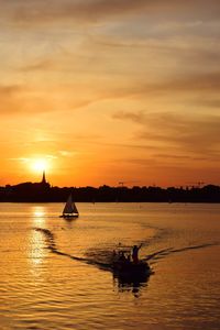 Silhouette boats in sea against sky during sunset