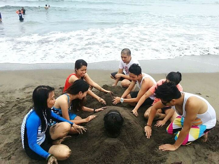 PEOPLE SITTING ON BEACH WITH SEA