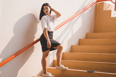 Young woman on staircase against wall