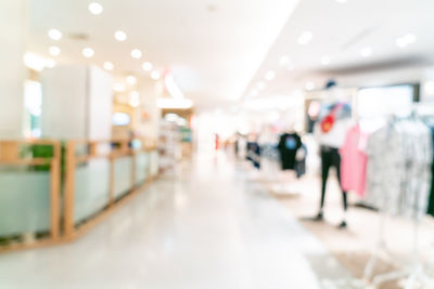 Defocused image of people walking on illuminated ceiling