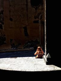 Woman sitting on wall of building