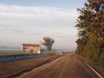 Road by trees against sky