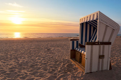 Sylt island beach scenery with hooded chair and sand at north sea, at sunset. german beach resort.