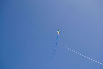 Low angle view of kite against clear blue sky