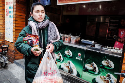 Full length portrait of woman standing against store