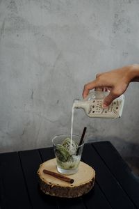 Midsection of man pouring coffee cup on table against wall