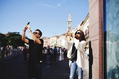 Friends photographing with smart phones while standing in city