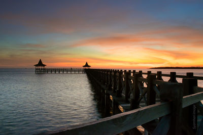 Pier over sea against sky during sunset