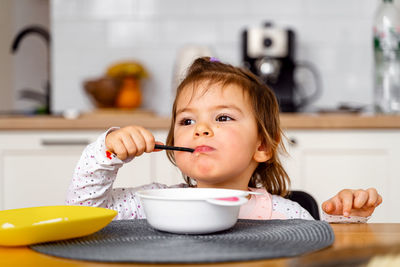 Cute girl eating food at table