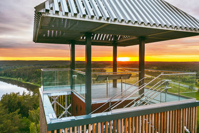 Lifeguard hut by lake against sky during sunset