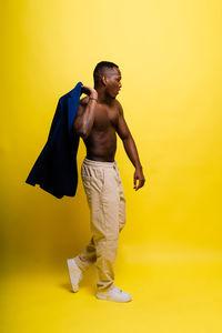 Side view of woman standing against yellow background