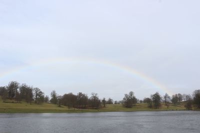 Scenic view of rainbow over lake against sky