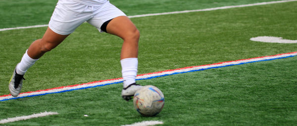 Low section of man playing soccer on court