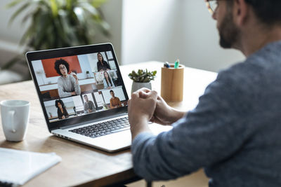 Mature businessman on video call through laptop with colleagues at home