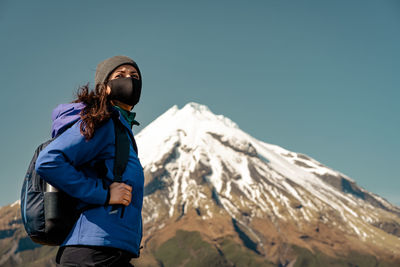 Man standing on snowcapped mountain against blue sky