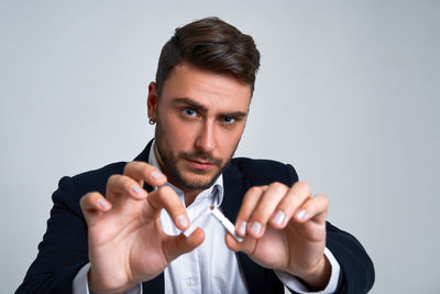 Portrait of young man making face against gray background