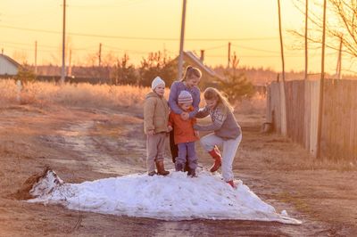 Full length of mother and daughters standing on snow over road