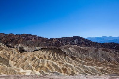 View of arid landscape against clear blue sky