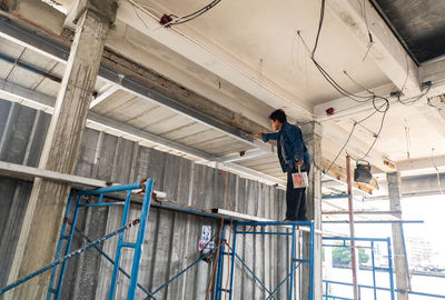 Low angle view of man working on ceiling