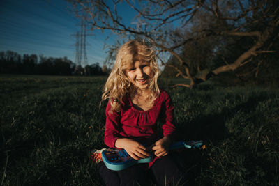 Girl playing with small guitar on field