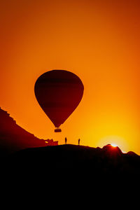 Silhouette hot air balloon against orange sky