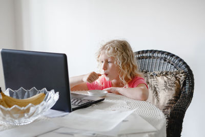 Cute girl eating food while looking at laptop