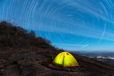 Illuminated tent on field against star field at night