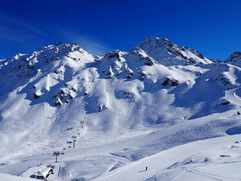 Scenic view of snowcapped mountains against blue sky on sunny day