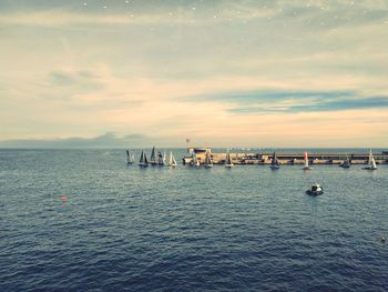 Sailboats in sea against sky during sunset