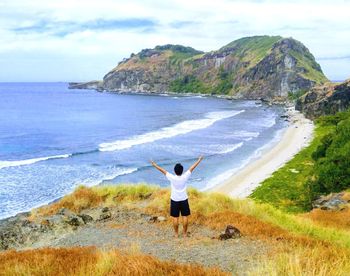 Rear view of man on beach against sky