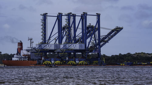 Cranes at commercial dock against sky