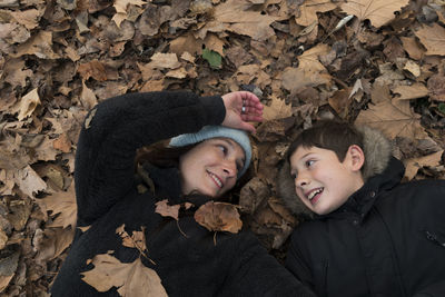 High angle view of mother and son lying down on ground during autumn