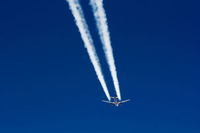 Low angle view of airplane and vapor trail in sky