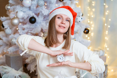 Portrait of smiling young woman holding christmas tree